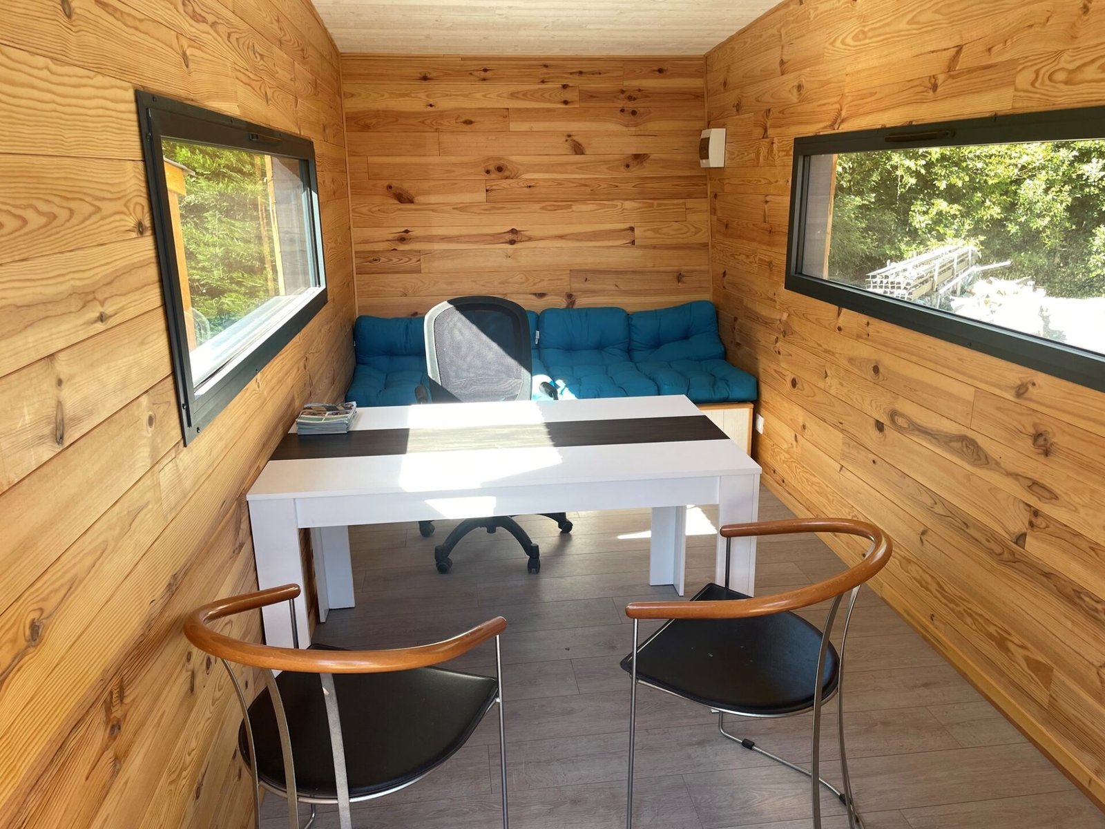 Intérieur d’une tiny house moderne aménagée en espace de bureau. Parfaite pour créer un bureau fonctionnel dans un espace réduit.